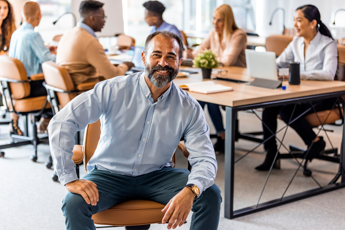 Man sitting down in a chair in a work space smiling